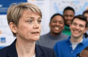 Home Secretary Expands Deport Now Appeal Later Policy to 15 New Countries Alt Text: Diverse community group discussing the deport now appeal later policy expansion, with a focus on its impact on foreign nationals in a UK town hall.