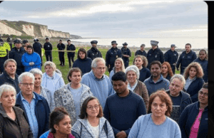 Tragic Incident on Isle of Sheppey: Kent Community in Shock Alt Text: Community gathering near Isle of Sheppey with police presence, reflecting the Tragic Incident on Isle of Sheppey, featuring a somber mood and supportive signs.